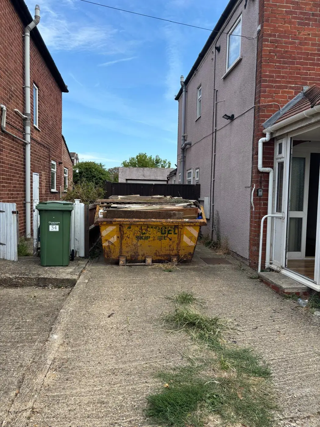 Skip filled with timber and household waste outside a residential property