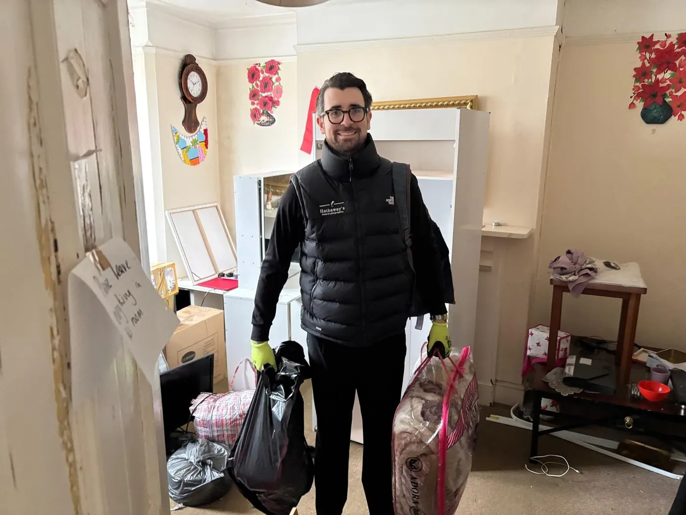 House clearance in progress with a team member carrying bagged waste out of a part-cleared room