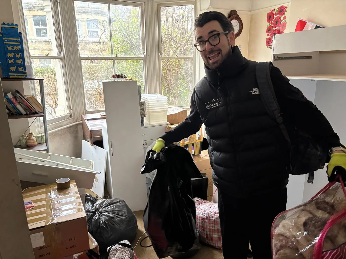 House clearance team member removing bagged household items from a furnished room