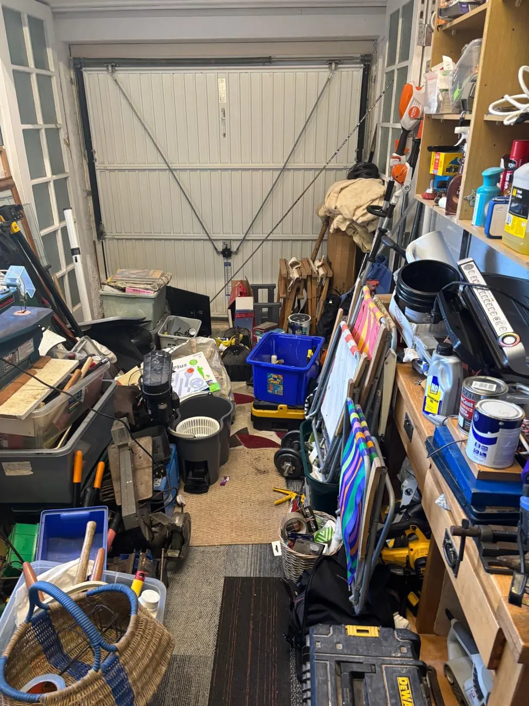 Overfilled garage with tools, paint tins and storage boxes ready for clearance