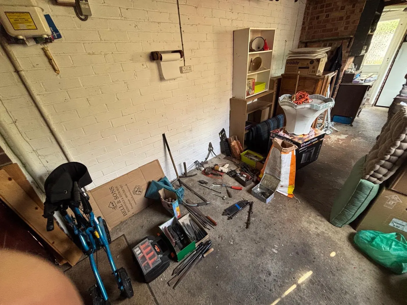 Garage workshop with tools and household items spread across the floor before clearance