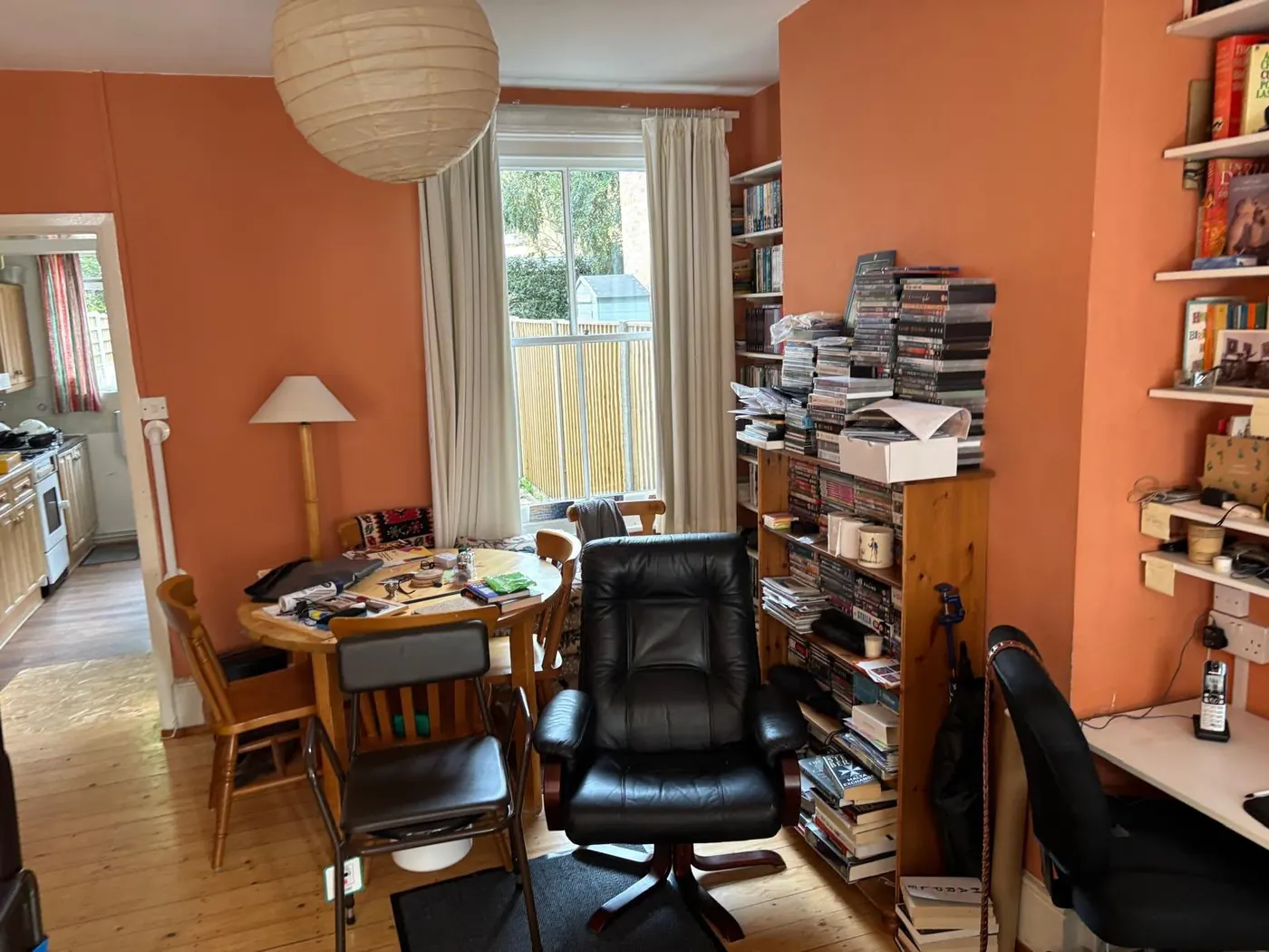 Cluttered dining room filled with books, media and furniture before a hoarding clearance