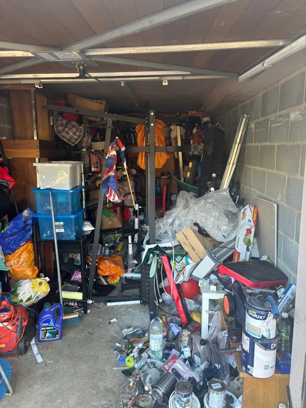 Crowded garage with shelving, tools, bags and containers before being cleared